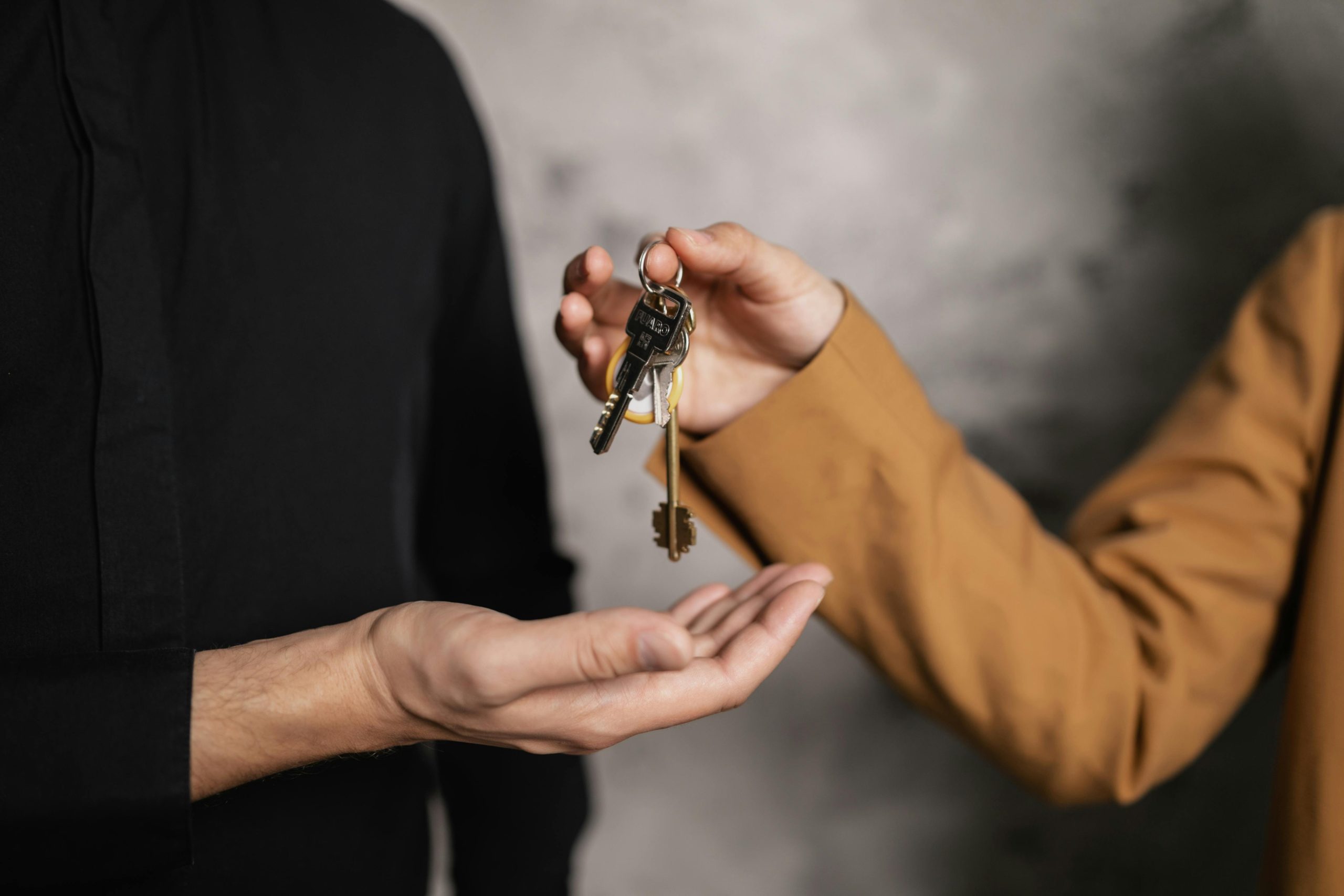 Image of a hand handing over a bundle of keys to another.